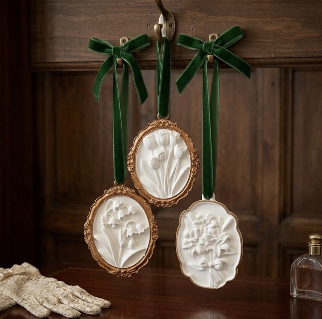 The three Alibi Collection gypsum diffusers hanging from green velvet ribbons against dark panelling