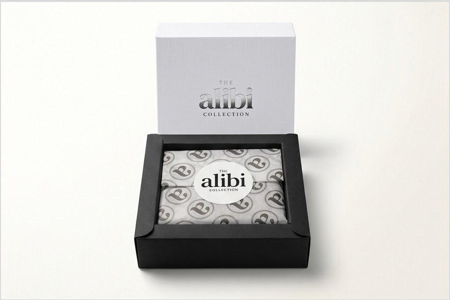 An Alibi Collection diffuser in its white and black signature gift box, wrapped in branded tissue