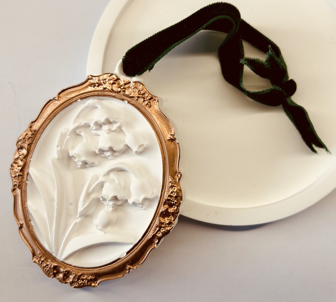 The Boudoir gypsum diffuser, a plaster lily-of-the-valley relief in a gold-painted frame with green velvet ribbon