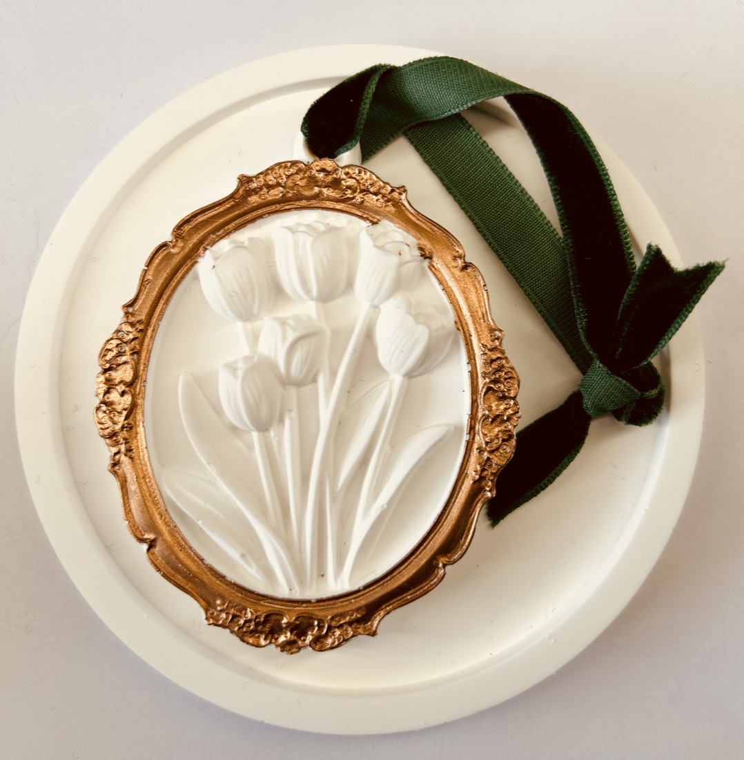 The Parlour gypsum diffuser, a plaster tulip relief in a gold-painted frame with green velvet ribbon